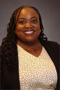 Professional headshot of smiling woman with braids, polka-dot blouse and black blazer
