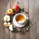 Image of a cup of tea with apples and berries around it