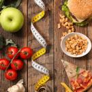 Low-fat veggies and fruits like broccoli, apples, tomatoes shown on left and high-fat foods like hamburgers, pizza and french fries on the right. A tape measure divides the two sides. UC Davis researchers find that switching from a high-fat to a low-fat diet slowed precancerous changes in the pancreas of mice. (Getty)